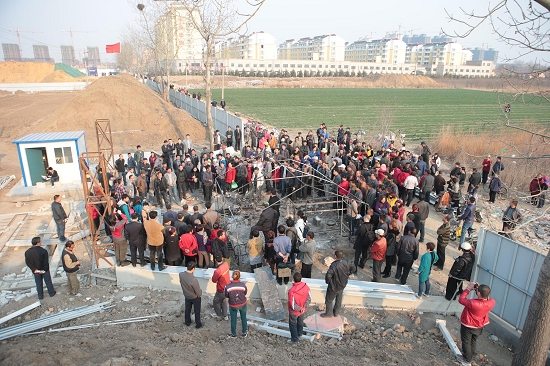 昨日,平度市凤台街道杜家疃村,村民在被烧毁的帐篷处围观.